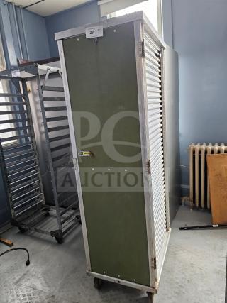 Sheet pan rack/cabinet with green panel, metal frame, and rolling wheels. Features serial label "CMF", in used condition.