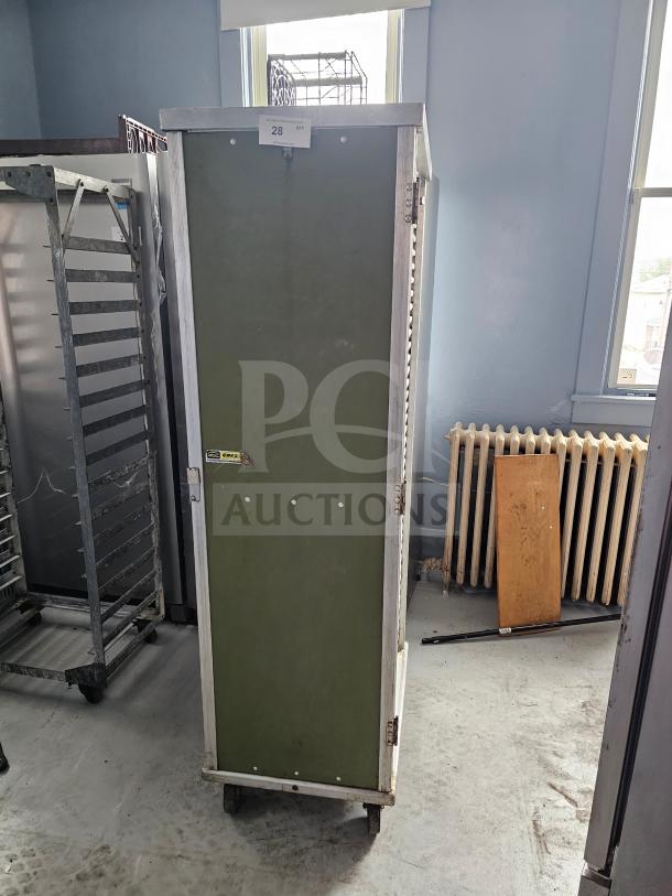 Green sheet pan rack/cabinet with metal frame, on wheels, labeled "CHM3". Cabinet door closed, visible wear on edges.