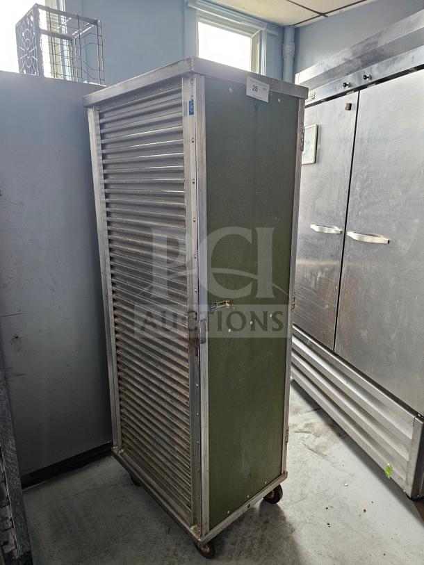 Sheet pan rack/cabinet with metal exterior, corrugated sliding door, on casters. Visible label: "Cres Cor." Good condition.