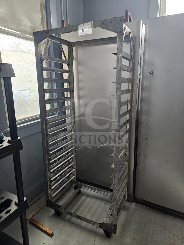 Aluminum sheet pan rack with multiple slots, on caster wheels, in used condition. Suitable for commercial kitchens.