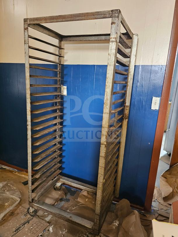 Aluminum sheet pan rack with 20 slots, visible wear and rust, four caster wheels, suitable for commercial kitchens.