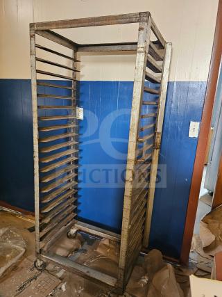 Aluminum sheet pan rack with 20 slots, visible wear and rust, four caster wheels, suitable for commercial kitchens.