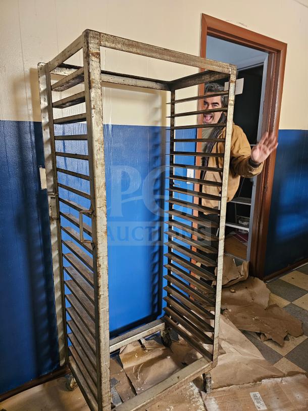 Aluminum sheet pan rack with 18 slots, worn condition, on caster wheels. Suitable for commercial kitchens.