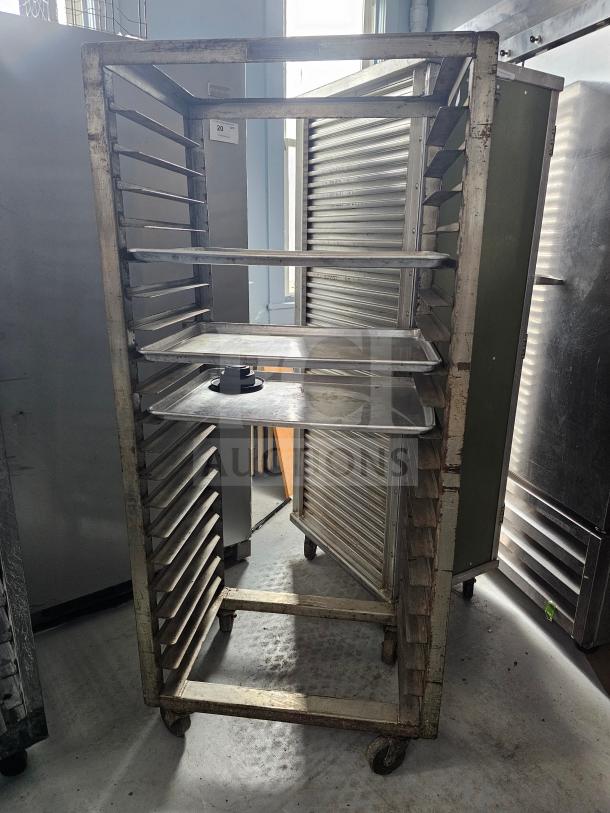 Aluminum sheet pan rack with multiple slots, used condition, on wheels for easy mobility. Suitable for commercial kitchens.