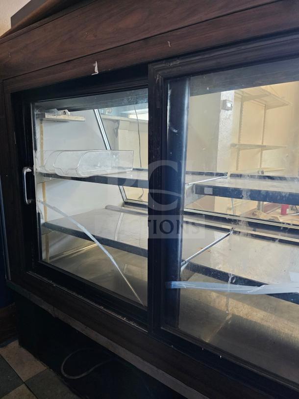 Fogel refrigerated deli display case with multiple signs of wear and non-functional condition, featuring glass doors and interior shelving.