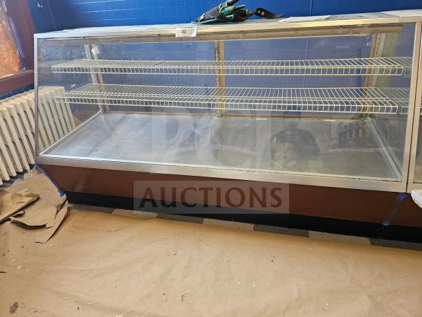 Commercial display case with two wire shelves, glass front, and wood base. Good condition. Tag number 33 visible on top.