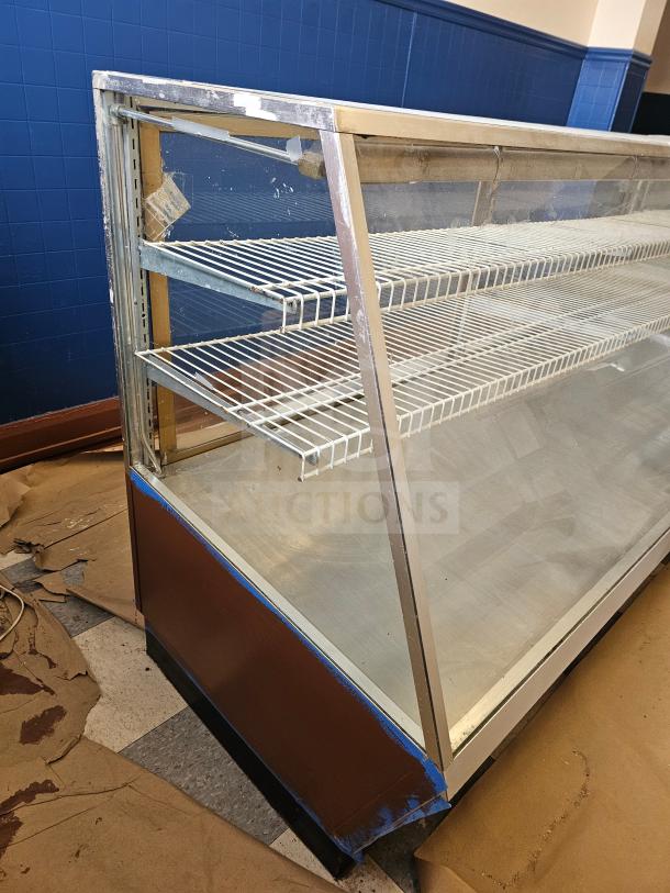 Glass commercial display case with two wire shelves. Shows wear on frame. Ideal for showcasing products.