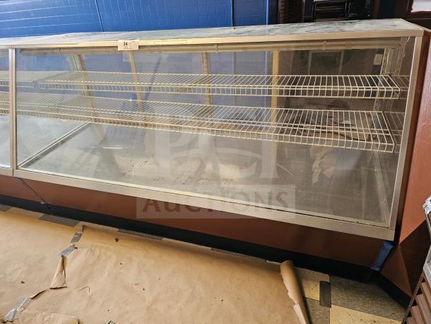 Commercial display case with glass front, metal shelves, and wooden base. Tag labeled "34". Used condition.