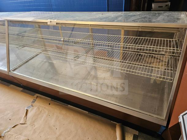 Commercial display case with glass front, metal frame, and two wire shelves. Good condition, some surface wear.