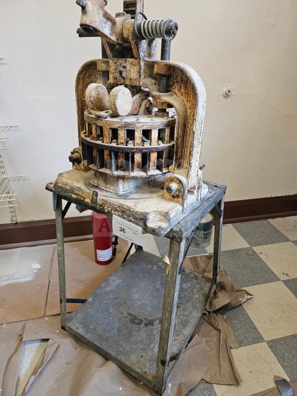 Dutchess Tool Company dough divider, worn metal, mounted on a metal stand, tag number 36 visible, vintage condition.