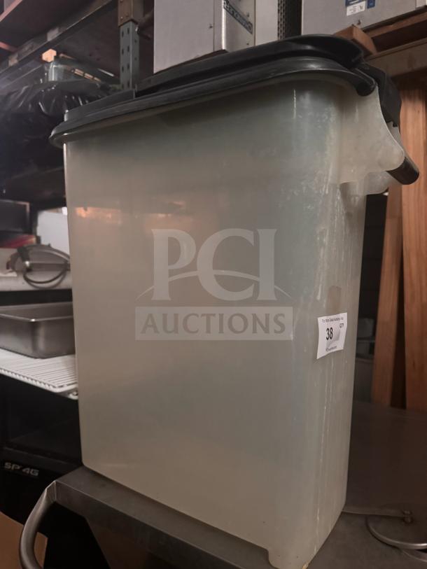 Translucent plastic food storage container with black lid, numbered tag "38" attached, in good condition.