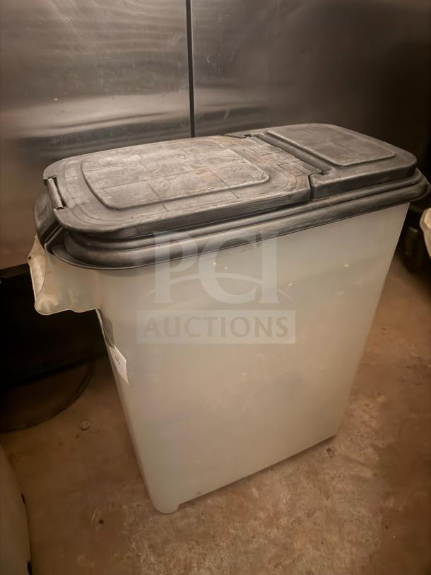 Durable plastic storage food container with a hinged lid, visible wear, and attached label. Ideal for bulk food storage.