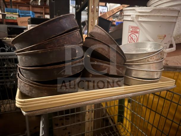 Stack of metal round baking pans, mixed patina; some show wear and oxidation. Ideal for vintage kitchen enthusiasts.