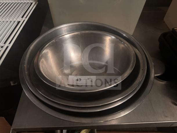 Stainless steel mixing bowls, nested set, smooth finish, visible auction tag "43 QTY 4," indicating condition and quantity.