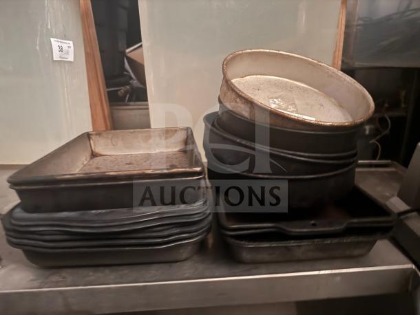 Lot of 17 miscellaneous baking pans, varied shapes, used condition, includes round and square pans, visible wear.