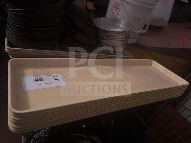 Beige plastic tray stack, rectangular shape, with a label reading "45, QTY 12, PCIAuctions.com." Appears in good condition.