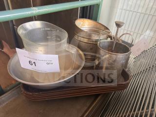 Miscellaneous kitchenware items including a measuring cup, metal sifter, and frother, all placed on a tray. Condition varies.