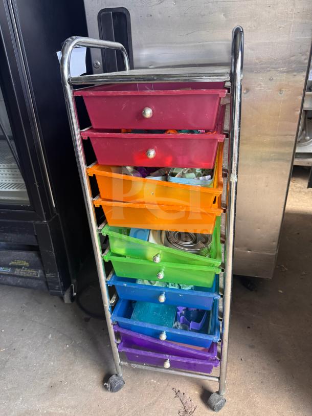 Colorful rolling storage cart with seven drawers, metal frame, and wheels. Drawers show various items inside. Good condition.