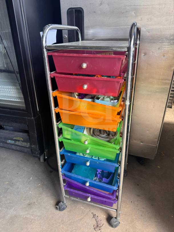 Colorful rolling storage cart with chrome frame and seven plastic drawers in varying colors; slightly open and filled.