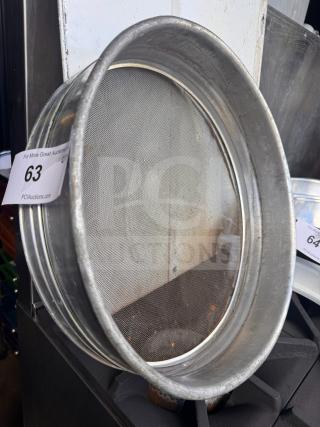 Aluminum flour sifter with fine mesh screen, in used condition. Auction tag reads "63 PCAuctions.com."