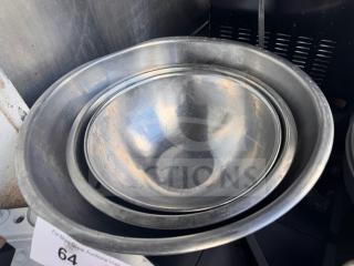 Lot of 3 aluminum mixing bowls, nested for storage, showing wear and scratches. Auction tag with number 64 visible.