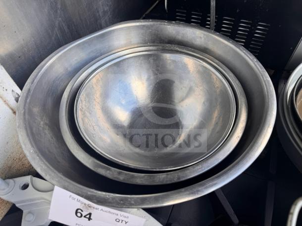 Lot of 3 stainless steel mixing bowls, used condition, nested. Auction tag visible with number 64.