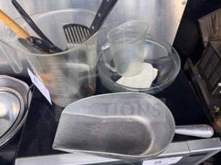 Mixed kitchenware lot includes plastic measuring cups, metal scoop, glass bowl, utensils. Used condition, sold together.