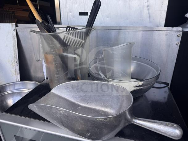 Miscellaneous kitchenware set including measuring jugs, mixing bowls, utensils, and metal scoop. Condition varies.