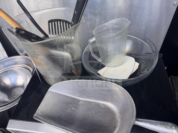 Miscellaneous kitchenware lot with measuring jugs, stainless steel bowls, utensils, and metal scoop; all items included as a set.