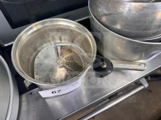 Vintage metal food mill with a hand-crank handle and perforated strainer, in used condition. Auction tag visible: "67 QTY 1".