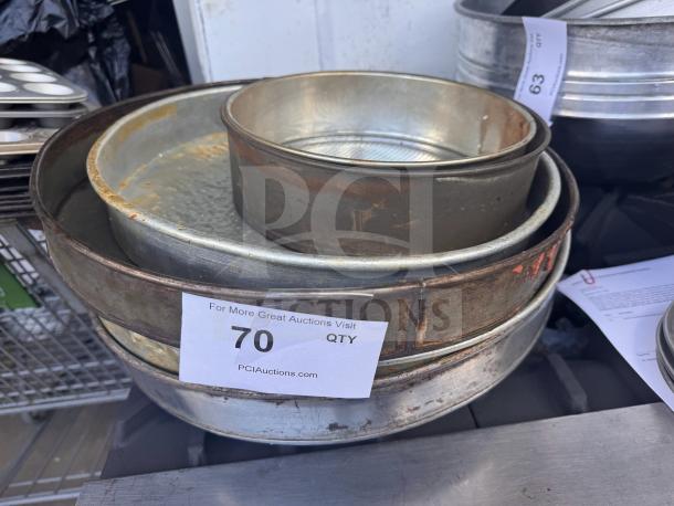 Lot of 5 assorted baking pans, various sizes and conditions, some rust visible. Auction tag reads "70 Qty" from PCIAuctions.com.