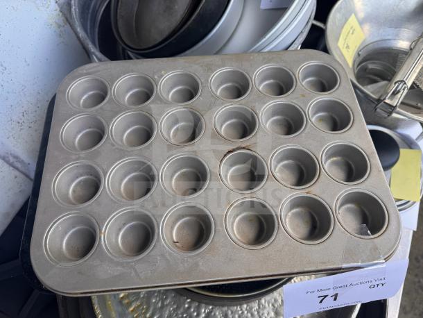 Aluminum muffin pan with 24 cups, showing signs of use with some discoloration. Auction label marked "71."
