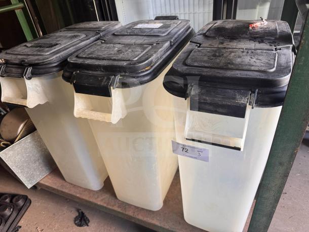 Three large plastic storage food containers with black lids, moderate wear, auction label "72 QTY 3" visible on one.