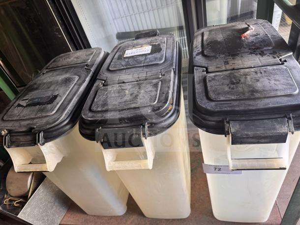 Three translucent food storage containers with black lids, showing signs of use and labels for identification.
