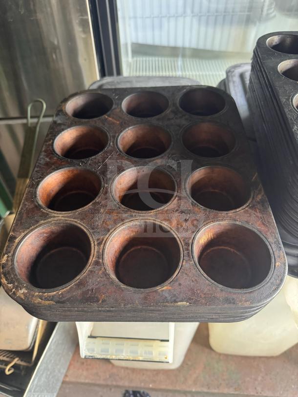 Aluminum muffin pan with 12 cups, pre-owned with signs of use on the surface, ideal for baking enthusiasts.