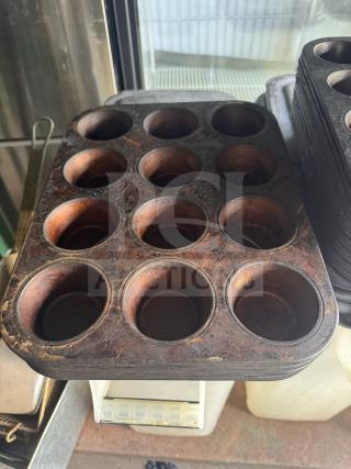 Aluminum muffin pan with 12 cups, pre-owned with signs of use on the surface, ideal for baking enthusiasts.