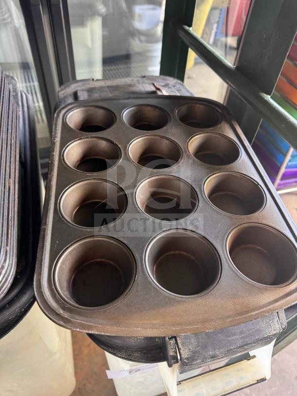 Aluminum muffin pan with 12 cups, slightly worn surface, ideal for baking enthusiasts, no visible brand markings.