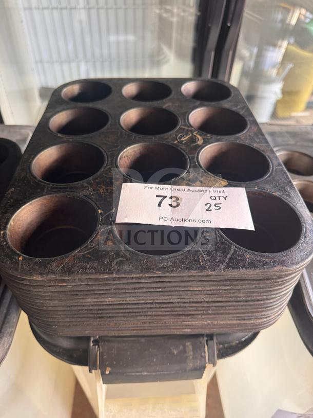 Aluminum muffin pan with 12 cups, showing signs of wear. Auction label indicates quantity and auction site information.