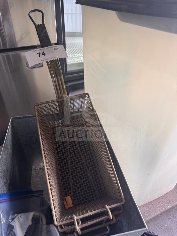 Metal fryer basket with wire mesh, rectangular shape, and black handle. Tag marked "74" visible. Used condition.