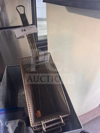 Metal fryer basket with wire mesh, rectangular shape, and black handle. Tag marked "74" visible. Used condition.