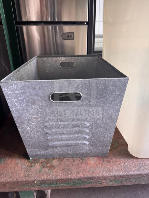 Steel galvanized utility bin with a textured finish, open top, and side handles. In good condition for storage use.