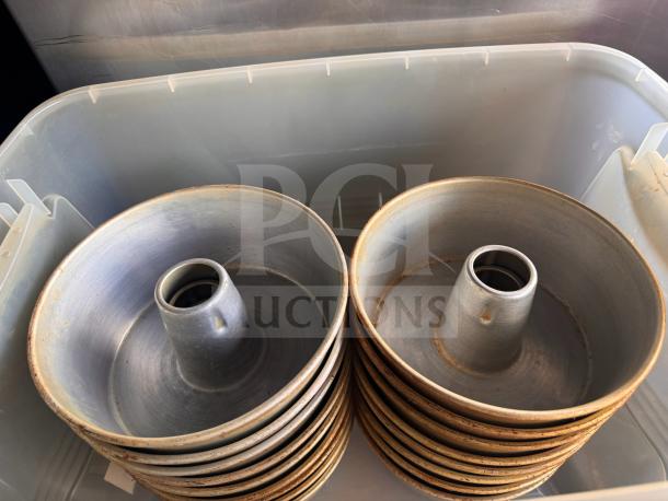 Metal tube cake pans, stacked, showing some wear. Ideal for baking, featuring central tube design for even cooking.