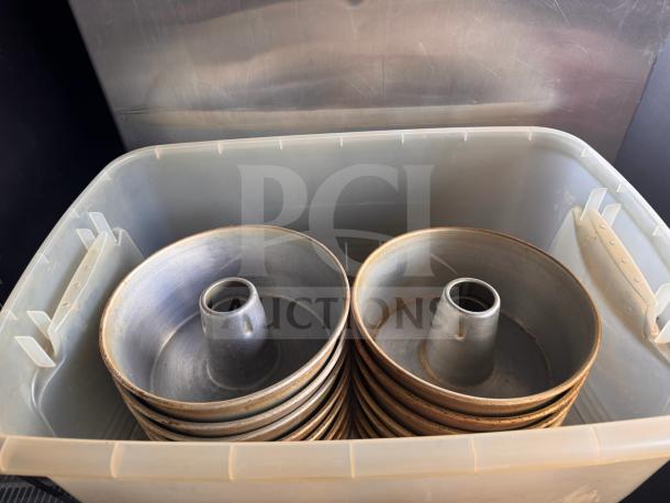 Stacks of tube cake pans in a plastic bin, showing a slightly worn, metallic surface, suitable for baking.