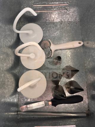 Miscellaneous baking and pastry tools including dough hooks, pastry cutter, spatula, and piping nozzles in a metal tray.