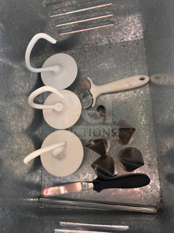 Miscellaneous baking and pastry tools, including dough hooks, pie cutter, offset spatula, and metal molds, in used condition.