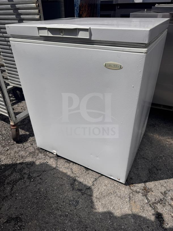Holiday white chest freezer, solid condition, visible logo on front. Ideal for extra storage. Slight wear on exterior.