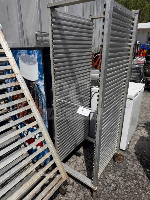 Industrial sheet pan rack on wheels, sturdy metal construction, multiple slots, used condition, auction tag "85".