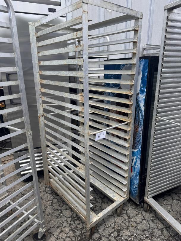 Rolling sheet pan rack with multiple shelves, metal construction, visible wear, includes auction tag indicating lot number.