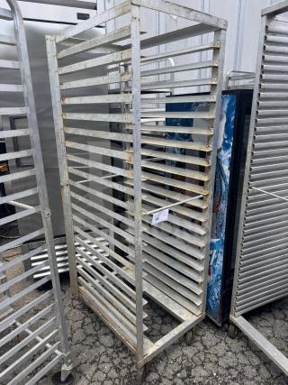 Rolling sheet pan rack with multiple shelves, metal construction, visible wear, includes auction tag indicating lot number.