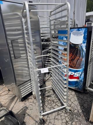 Metal sheet pan rack with multiple shelves, on wheels. Numbered label "87," indicating auction lot. Good condition.